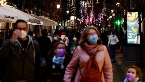 Los transeúntes, con una máscara facial como protección contra el COVID-19, caminan frente a las luces navideñas en las calles de Madrid, el 22 de diciembre de 2021. (Foto de JAVIER SORIANO / AFP)