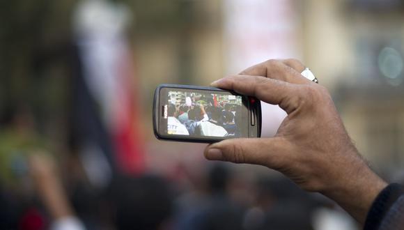 En esta foto de archivo tomada el 24 de noviembre de 2011, un hombre usa su teléfono celular para registrar la actividad de otros manifestantes antigubernamentales durante una manifestación masiva en la plaza Tahrir de El Cairo, Egipto, durante la Primavera Árabe. (Foto de Odd ANDERSEN / AFP).