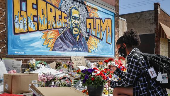 Miles de personas han salido a las calles tras la muerte de George Floyd ocurrida el 25 de mayo de 2020. En la imagen, una mujer deja un arreglo floral frente a un mural que recuerda a Floyd. (Foto: AP/John Minchillo)