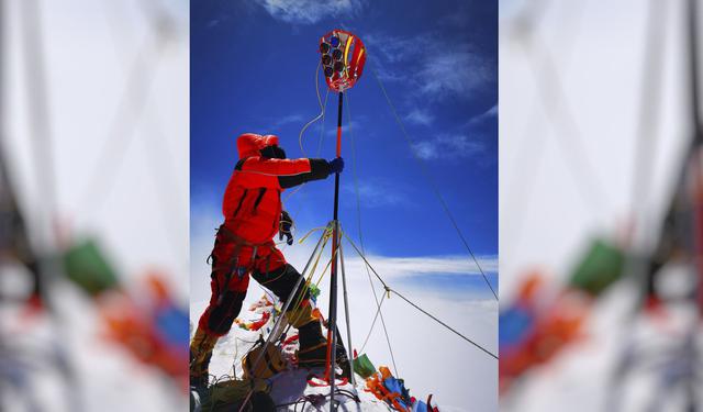 Un miembro de un equipo de topografía chino instala un equipo de prospección en la cumbre del Monte Everest, también conocido localmente como el monte. Qomolangma. Este hecho se da en un momento en que el pico más alto del mundo se ha cerrado a los escaladores comerciales. (Tashi Tsering / Xinhua vía AP)