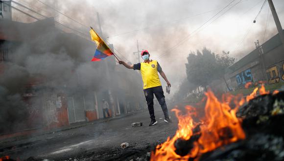 Un manifestante sostiene una bandera de Ecuador junto a una fogata, mientras los manifestantes bloquean la calle durante una protesta antigubernamental en medio de un punto muerto entre el gobierno del presidente Guillermo Lasso, en Quito, Ecuador.