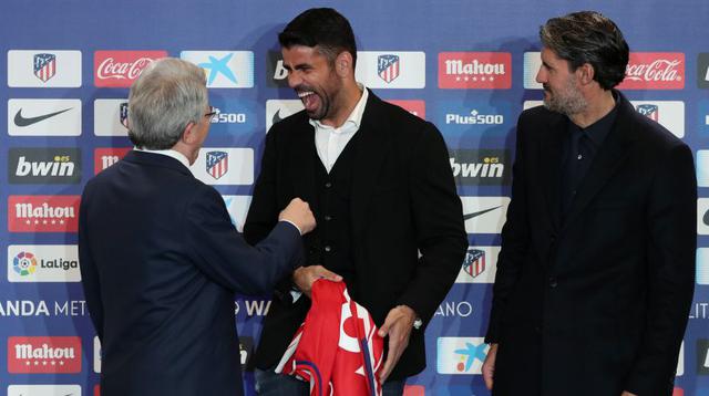 Diego Costa estrecha la mano de Enrique Cerezo, presidente del Atlético de Madrid, mientras que con la otra sostiene su camiseta. (Foto: AFP)