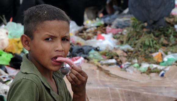 Un niño come una salchicha que encontró en un basurero municipal ubicado al norte de Tegucigalpa, en Honduras. (Foto: AFP)