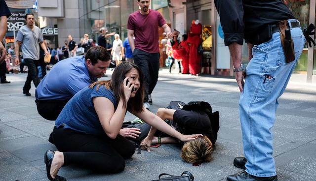 EDITORS NOTE: Graphic content / People attend to an injured man after a car plunged into him in Times Square in New York on May 18, 2017.  A car plowed into a crowd of pedestrians in New York's bustling Times Square, leaving one person dead and at least 12 other injured in what officials said was an accident.
 / AFP / Jewel SAMAD