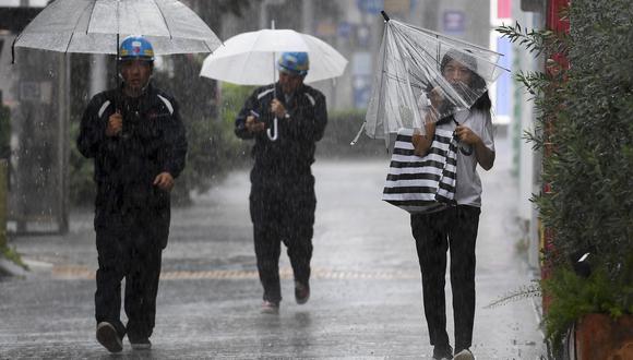 Los peatones desafían los elementos en el distrito de Aoyama de Tokio el 12 de octubre de 2019, cuando los efectos del tifón Hagibis comienzan a sentirse en la capital de Japón. (Foto: AFP)