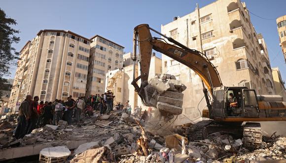 Una excavadora limpia los escombros de un edificio, después de que fuera golpeado por ataques de Israel en la ciudad de Gaza, el 16 de mayo de 2021. (Foto de MOHAMMED ABED / AFP).
