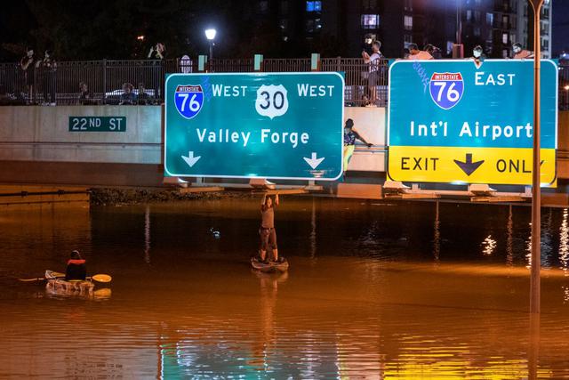 Un kayakista posa para una foto debajo de un letrero de la carretera después de las inundaciones causadas por las fuertes lluvias del huracán Ida en Filadelfia, Pensilvania, el 2 de septiembre de 2021. (BRANDEN EASTWOOD / AFP).