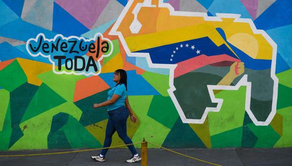 A pedestrian walks past a mural that reads "All of Venezuela," during a referendum vote in Caracas, Venezuela, on Sunday, Dec. 3, 2023. Following massive offshore oil discoveries in the region by Exxon Mobil Corp. and others, and with elections approaching, President Maduro is inflaming regional tension by reviving a long-dormant border dispute over the area known as the Essequibo. Photographer: Gaby Oraa/Bloomberg
