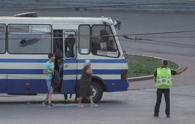 Un oficial de policía dirige a tres rehenes liberados de un autobús secuestrado en el centro de la ciudad de Lutsk, Ucrania. (EFE / EPA / MARKIIAN LYSEIKO).
