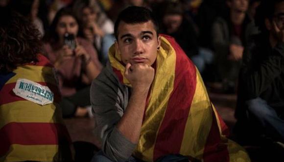 Un joven escucha la comparecencia de Mariano Rajoy en una pantalla de televisión de Barcelona el día del intento de referéndum en Cataluña.