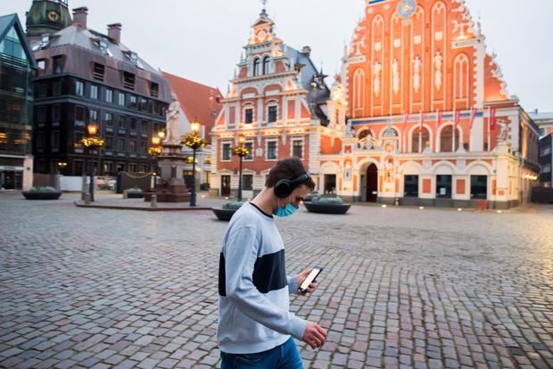 A man wearing a face mask walks past an empty square during the first day of restrictions due to the coronavirus pandemic in Riga, Latvia, on November 9, 2020 (Gints Ivuskans / AFP).