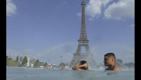Un grupo de personas se refresca en una fuente en París, Francia. (AP).