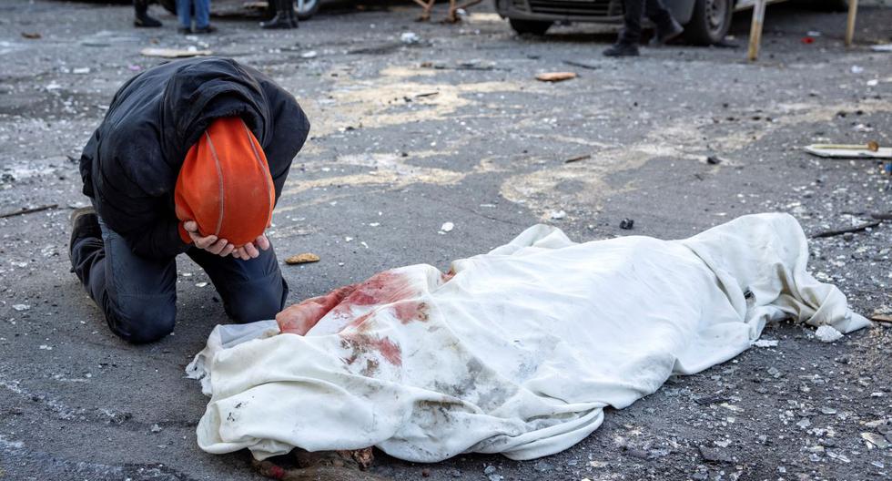 Una persona llora junto a un cuerpo envuelto cerca de un edificio residencial que fue alcanzado por los bombardeos de Rusia sobre Kiev, Ucrania, el 17 de marzo de 2022. (FADEL SENNA / AFP).