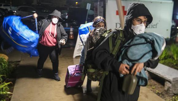 Personas con sus pertenencias llegan a un centro de evacuación en Santa Bárbara, California, el lunes 9 de enero de 2023. (Foto AP/Ringo HW Chiu).