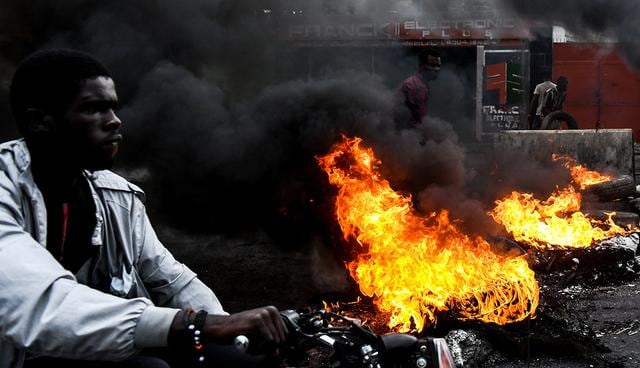 Un hombre pasa junto a neumáticos en llamas durante una protesta contra la escasez de combustible y para exigir la renuncia del presidente Jovenel Moise, en Puerto Príncipe, Haití. (Foto: AFP)