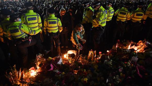 Una mujer coloca un tributo a Sarah Everard desde un espacio abierto por el cordón policial en Clapham Common, al sur de Londres, el 13 de marzo de 2021. (Foto de JUSTIN TALLIS / AFP).