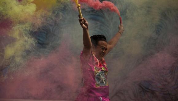 Marven, una mujer transgénero del estado de Oaxaca, lanza coloridas bengalas de humo durante su evento de campaña para un asiento en el Congreso de la Ciudad de México, afuera de un restaurante el sábado 29 de mayo de 2021. (AP Foto/Fernando Llano).