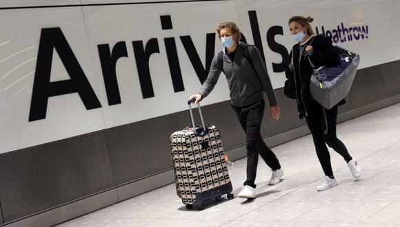 Dos personas llegan a la Terminal 5 del aeropuerto Heathrow en el oeste de Londres, Reino Unido, el 30 de noviembre de 2021, cuando se introducen nuevas restricciones debido a la variante ómicron del coronavirus. (Adrian DENNIS / AFP).