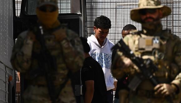 La Guardia Nacional del Ejército de Texas observa cómo migrantes suben a un autobús tras de entregarse a los agentes de la Patrulla Fronteriza de Aduanas y Protección Fronteriza (CBP) de EE.UU. , en El Paso, Texas, el 12 de mayo de 2023. (Foto de Patrick T. Fallon / AFP)