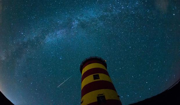 Una estrella fugaz cruza el cielo nocturno detrás del faro de Pilsum, en el noroeste de Alemania, durante el pico de actividad de la lluvia anual de meteoros de las Perseidas el 13 de agosto de 2015 (Foto: Matthias Balk / DPA / AFP)
