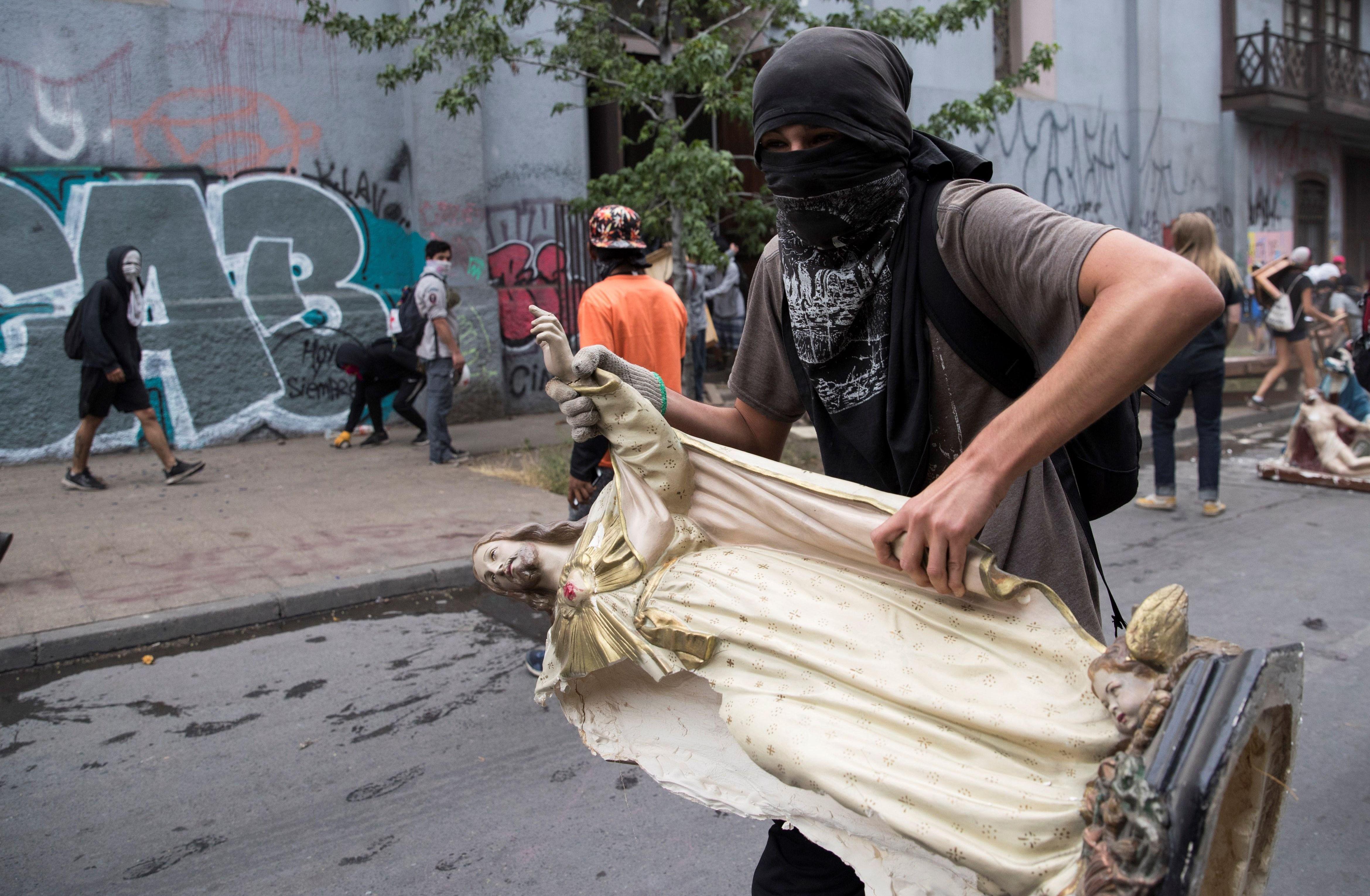 Manifestantes retiran objetos de la Parroquia de La Asunción durante una protesta en contra del Gobierno. (EFE/ Orlando Barría).