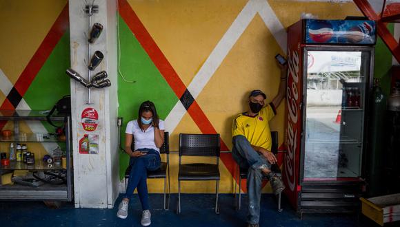 Dos empleados descansan en un taller mecánico propiedad de Remberto Herrera, colombiano que vice hace 38 años en Venezuela, el 08 de octubre del 2021, en Caracas. (Foto: EFE/ Miguel Gutiérrez)