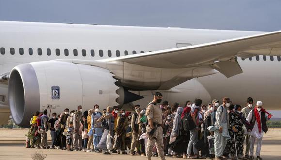 Los afganos que fueron transportados desde Afganistán caminan después de desembarcar en la base militar de Torrejón, España, el 23 de agosto de 2021. (AP Photo / Andrea Comas).