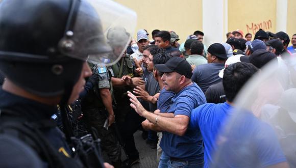 Votantes y policías luchan frente a un centro de votación que permanece cerrado tras presuntas amenazas e irregularidades durante las elecciones generales, en San José del Golfo, en las afueras del norte de la ciudad de Guatemala el 25 de junio de 2023 (Foto: Johan ORDÓNEZ / AFP)