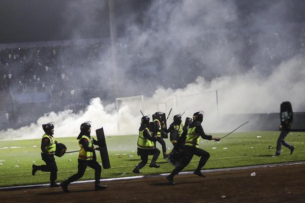 Policías corren mientras intentan evitar que los fanáticos del fútbol ingresen al campo durante un enfrentamiento en el estadio Kanjuruhan en Malang, Java Oriental. (EFE/EPA/H. PRABOWO).