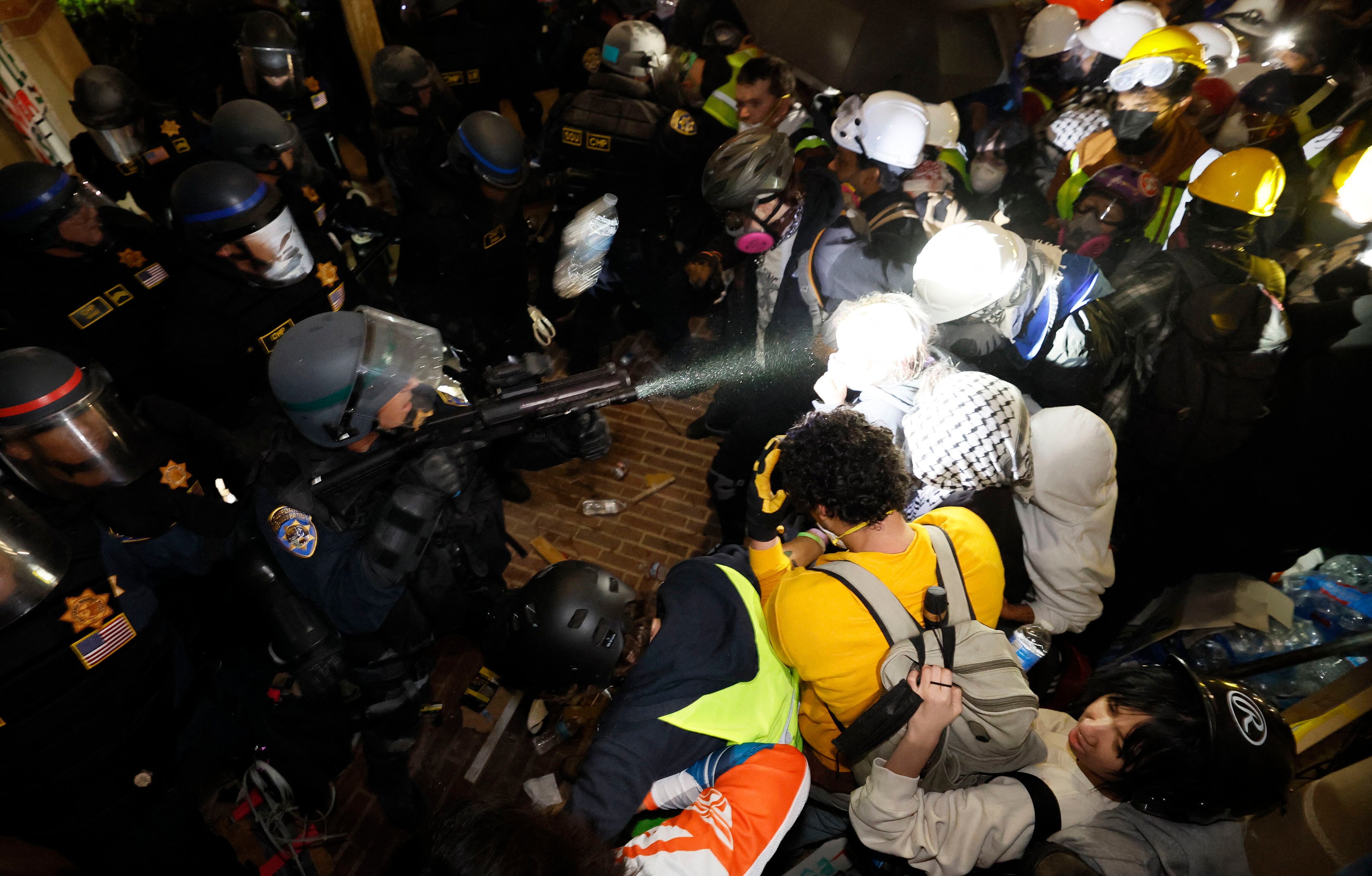 La policía se enfrenta a estudiantes pro-palestinos después de destruir parte de la barricada del campamento en el campus de la Universidad de California en Los Ángeles (UCLA), a primera hora del 2 de mayo de 2024. (Foto de Etienne LAURENT / AFP).