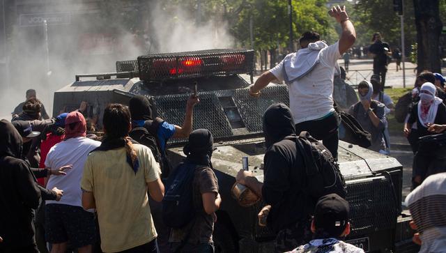 Los manifestantes rodean un vehículo de la policía en Santiago de Chile. (AFP / CLAUDIO REYES).