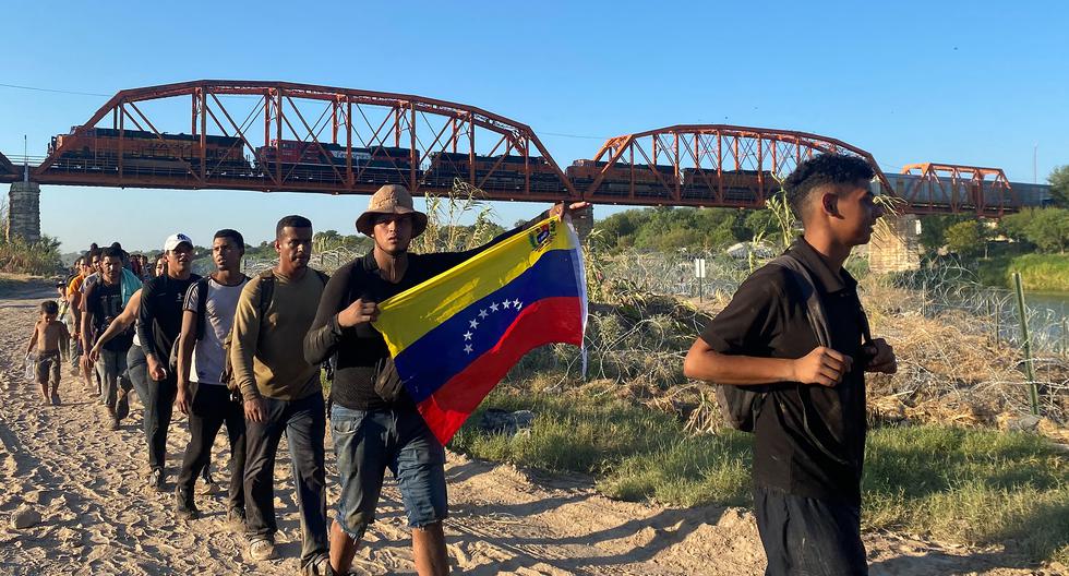 Jesús Ramírez, de 29 años y con una bandera de Venezuela, cruza a Estados Unidos desde México con cientos de venezolanos en Eagle Pass, Texas, el 23 de septiembre de 2023. (Foto de Paula RAMÓN / AFP).