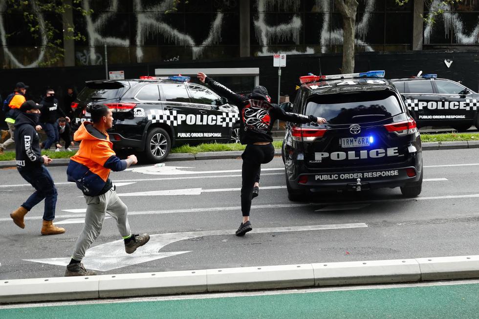 Los manifestantes persiguen a la policía durante una protesta contra la obligación de las vacunas contra el coronavirus en Melbourne, Australia, el 21 de septiembre de 2021. (STR / AFP).