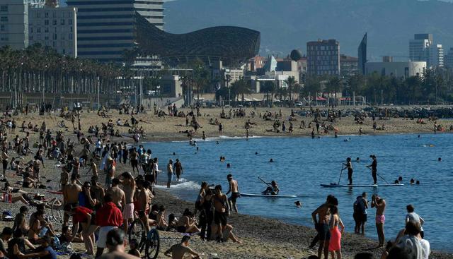 La gente toma el sol en la playa de la Barceloneta en Barcelona  durante las horas permitidas por el gobierno para hacer ejercicio, en medio del cierre nacional para evitar la propagación del coronavirus. (AFP / LLUIS GENE).