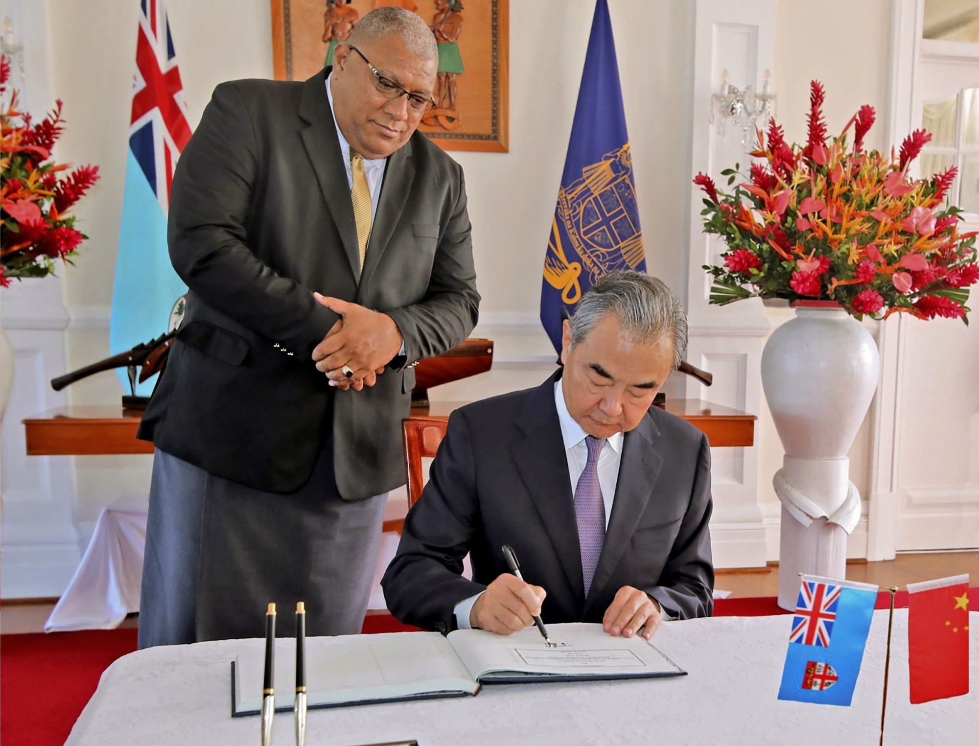 Fijian President Ratu Wiliame Katonivere hands Chinese Foreign Minister Wang Yi the illustrious guestbook for his signature.  (Fiji Government via AP)
