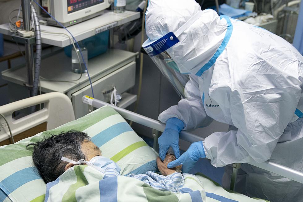 La imagen muestra a una enfermera sosteniendo la mano del paciente para consolarlo mientras está en la UCI. (Foto: AFP)