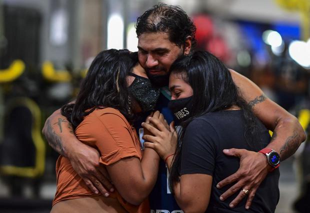 Raúl Gutiérrez abraza a sus hijas en su gimnasio en Lanús, provincia de Buenos Aires, Argentina, el 21 de abril de 2021. (Foto de RONALDO SCHEMIDT / AFP).