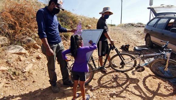 El maestro boliviano Wilfredo Negrete enseña a una niña en Aiquile, departamento de Cochabamba, Bolivia, el 12 de junio de 2020. Negrete monta su bicicleta durante varios kilómetros para dar lecciones a sus estudiantes en sus hogares en medio de la nueva pandemia de coronavirus.. (Foto por STR / AFP).