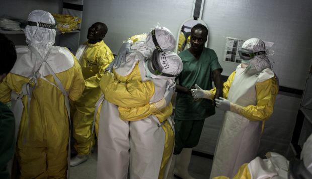 Trabajadores de la salud se abrazan mientras se ponen sus equipos de protección personal (PPE) antes de dirigirse a la zona roja en un nuevo centro de tratamiento de ébola. (Foto: AFP)