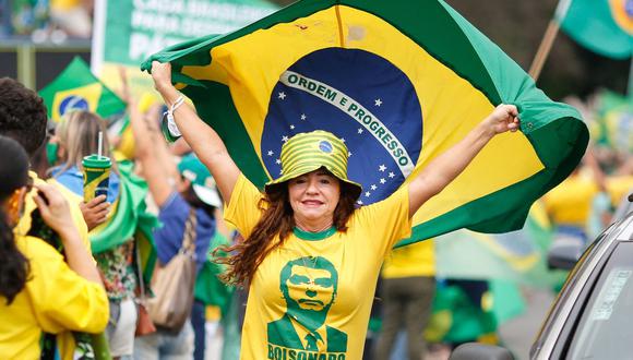 Una mujer sostiene una bandera brasileña durante una manifestación para mostrar su apoyo al presidente brasileño Jair Bolsonaro, en medio de la pandemia de coronavirus. (Foto de Sergio LIMA / AFP).