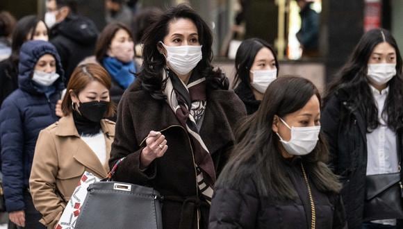 Personas con mascarillas cruzan una calle en Tokio el 27 de enero de 2023. (Foto de Yuichi YAMAZAKI / AFP)