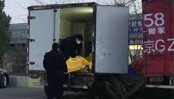 Operarios cargan bolsas para cadáveres en un camión en un complejo funerario en Beijing.