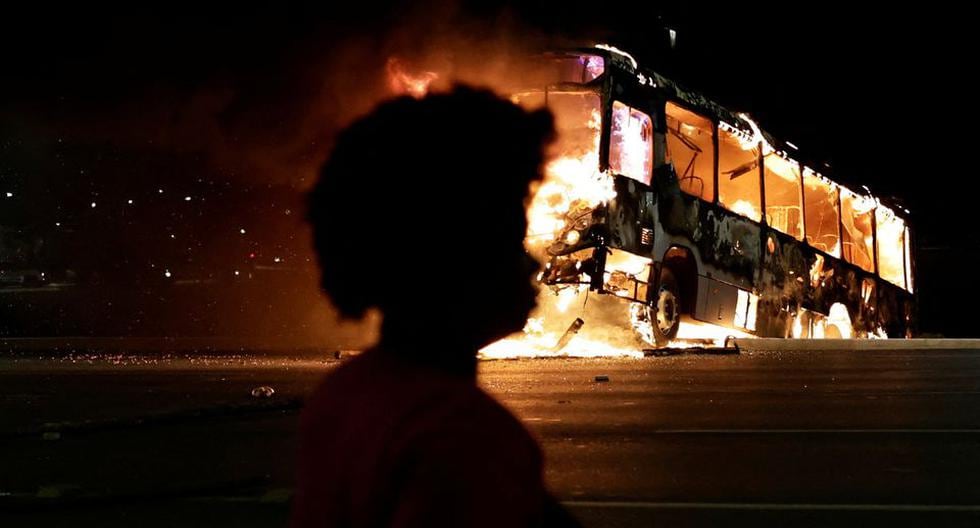 Una mujer camina cerca de un autobús en llamas mientras los partidarios del presidente de Brasil, Jair Bolsonaro, protestan después de que el juez ordenara el arresto del líder indígena José Acacio Serere Xavante. (REUTERS/Ueslei Marcelino).