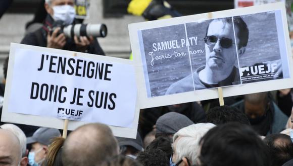 La gente sostiene un retrato del profesor de historia Samuel Paty mientras se reúnen en la Place de la République en París el 18 de octubre de 2020, dos días después de que fuera decapitado por un atacante. (Foto de Bertrand GUAY / AFP).