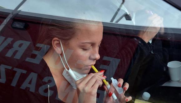 Una joven realiza un test de gárgaras desde su coche para detectar la COVID-19, hoy viernes, en el carril de test que la ciudad de Viena (Austria) ha montado junto al estadio de fútbol Ernst Happel. (EFE/Jorge Dastis)