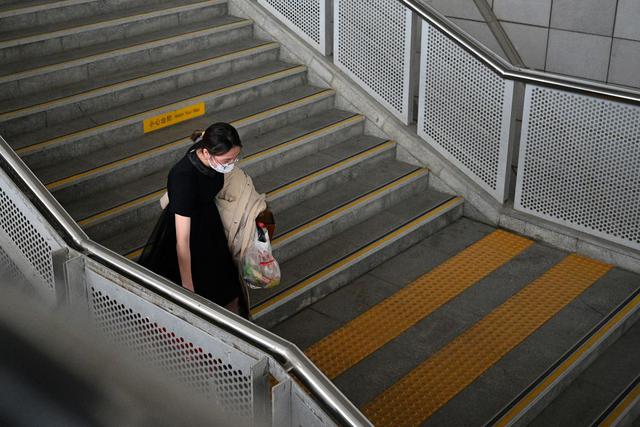 Un pasajero con una máscara facial baja las escaleras después de bajarse del tren al llegar a la estación de trenes de Macheng, en la provincia central de Hubei. (AFP)