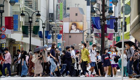 Los transeúntes con mascarillas caminan bajo la decoración de las calles de los Juegos Olímpicos y Paralímpicos de Tokio, en Tokio, el 14 de mayo de 2021. (REUTERS/Naoki Ogura).