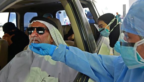 Una enfermera usa un hisopo para hacer una prueba de coronavirus al pasajero de un automóvil en Abu Dhabi, Emiratos Árabes Unidos, el 2 de abril de 2020. (GIUSEPPE CACACE / AFP).