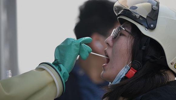 Un trabajador de la salud toma una muestra de hisopo a una mujer para la prueba del coronavirus Covid-19 en Beijing el 25 de octubre de 2021. (Noel Celis / AFP).