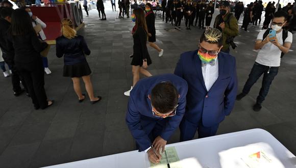 Una pareja firma documentos antes de casarse durante una boda colectiva igualitaria en el marco del mes del orgullo LGBTQ+, en la explanada del Registro Civil de la Ciudad de México el 24 de junio de 2022. (Foto de ALFREDO ESTRELLA / AFP)